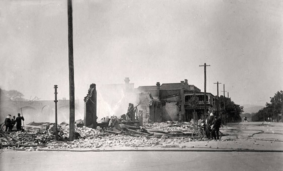 OUT OF THE ASHES: Crews clean up after the fire that destroyed T H Mate & Co’s store. The Courthouse Hotel is in the background. The store was rebuilt and reopened to the public in August 1916.