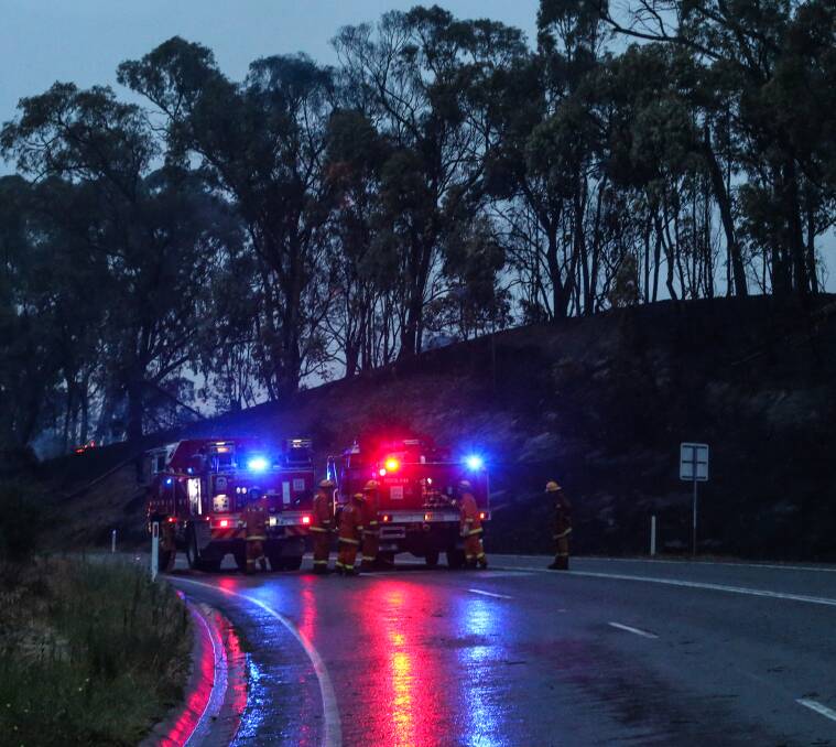 COOL CHANGE: Firefighters attend to burning logs on the Beechworth to Wodonga Road as the weather cools down. Picture: JAMES WILTSHIRE