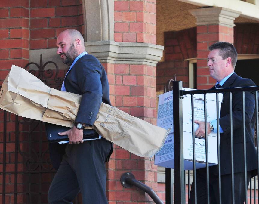 EVIDENCE: Detective  Senior Constable John Cosgrove and Detective Sergeant Darren Gunn carry evidence into Wagga courthouse.

