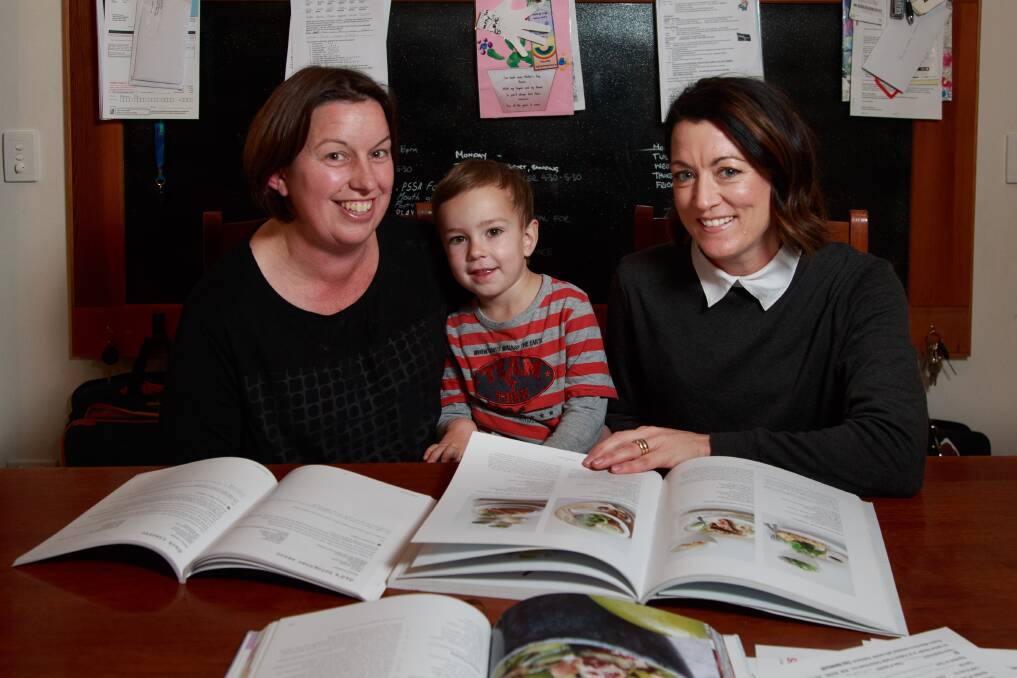 SHARED TABLE: Thurgoona's Pauline Goonan with son Alex Goonan, 3, and East Albury's Chelsea Frazer work on St Patrick's cookbook project. Picture: SIMON BAYLISS