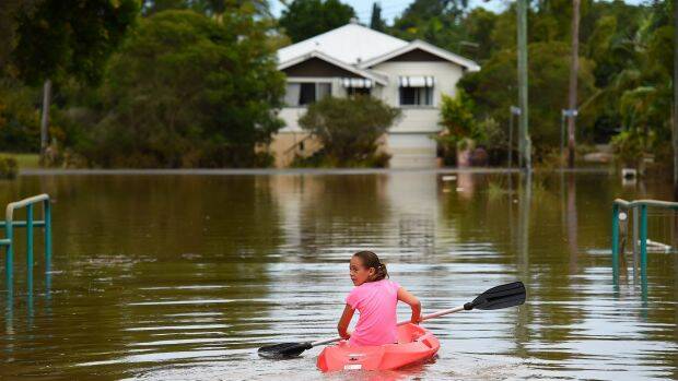 Maleah Jones, 8, canoes up flooded Bright street to her home in Lismore.  Photo: Kate Geraghty