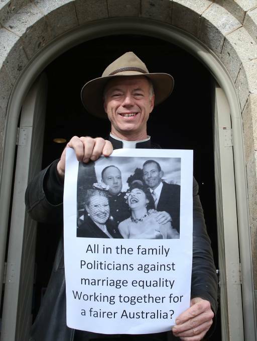 UNDER FIRE: St Matthew's Father MacLeod-Miller hangs posters in Albury on Monday in a hope to gain more support for marriage equality. Picture: ELENOR TEDENBORG