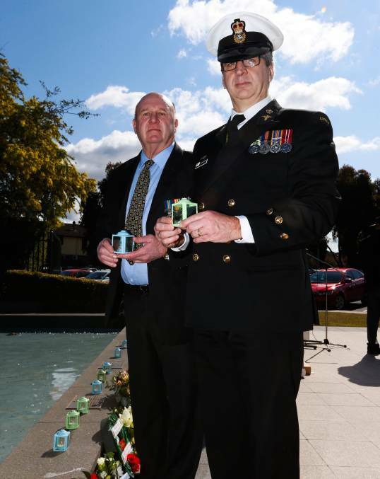 LEST WE FORGET: Bill Thompson and Chief Petty Officer John Blackstone, representing the Naval Association, hold candles at the memorial service. Picture: MARK JESSER
