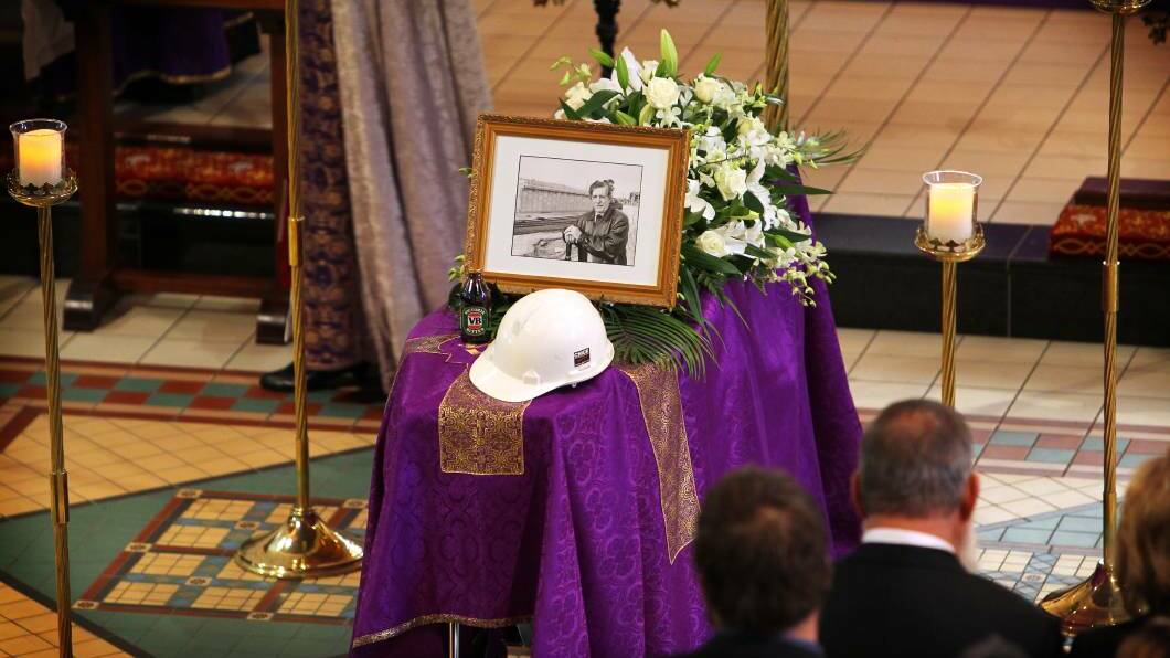 A photo of Maurice Chick, with a hardhat and a stubby of beer sits on top of the coffin during the service. Picture: MATTHEW SMITHWICK