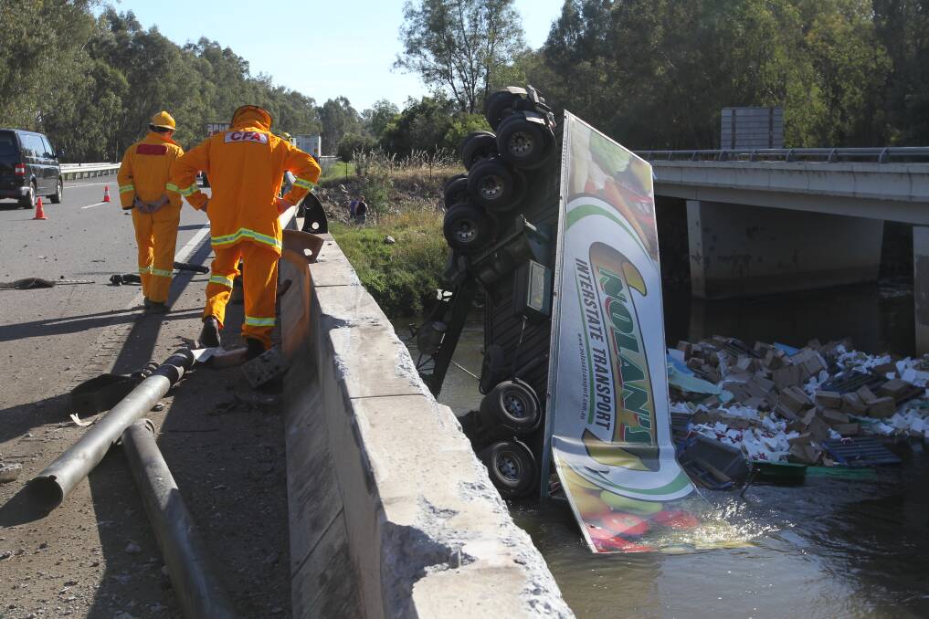 LUCKY ESCAPE: The driver of this truck was lucky to remove himself from this truck after it crashed from the Hume Freeway into the Ovens River. Pictures: SHANA MORGAN