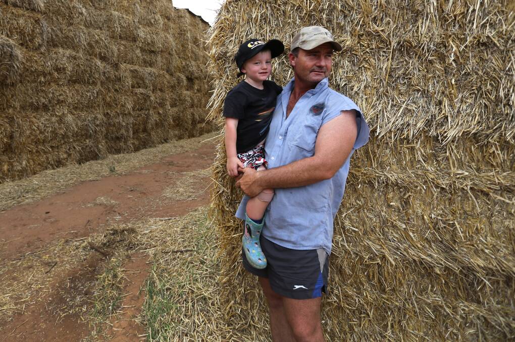 PIPE DREAM: Farmer Brendan Farrell, pictured looking over some donated hay with his son Sam, 4, at Burrumbuttock recently, wants to set up a pipeline to deliver a permanent water supply for the Queensland town of Ilfracombe.