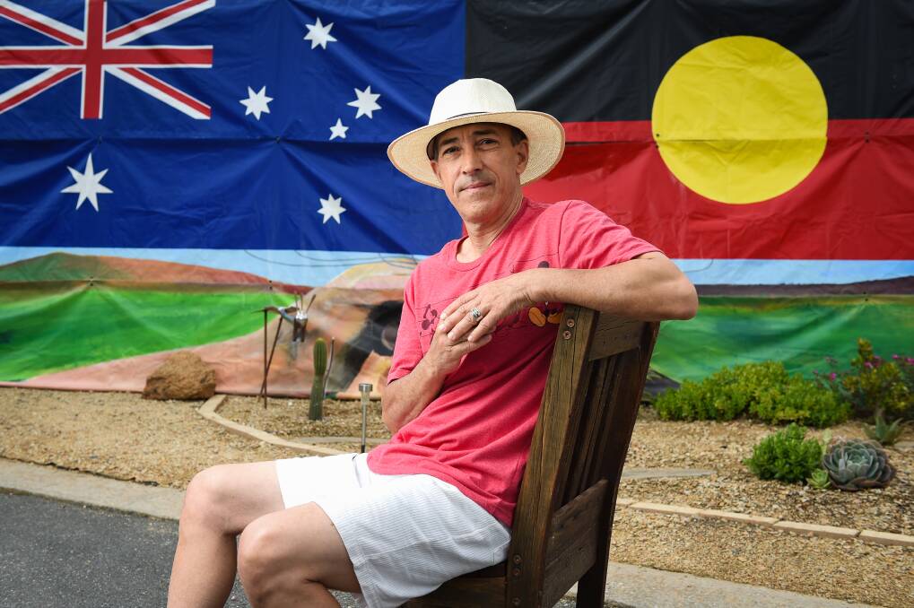 BIGGER PICTURE: Anthony Perrone, who migrated to Australia more than 20 years ago, with the banner he created for the Olympic Torch relay in 2000 while he was working in Alice Springs. Picture: MARK JESSER
