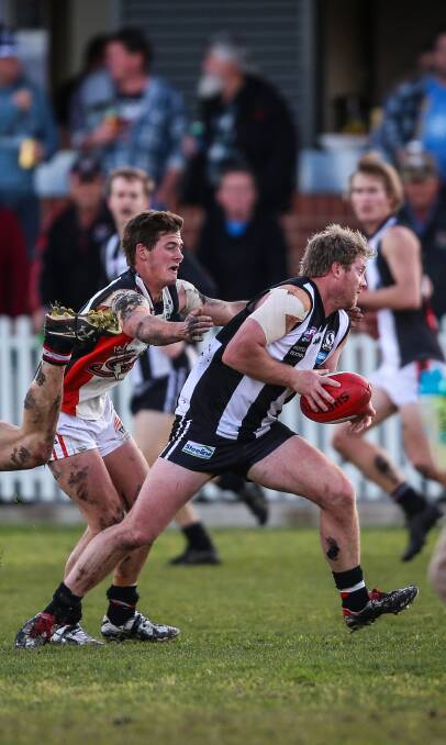 ON THE MARCH: Magpie Michael Sims attempts to break a tackle from Ronnie Boulton at Urana Road Oval on Saturday. Pictures: JAMES WILTSHIRE