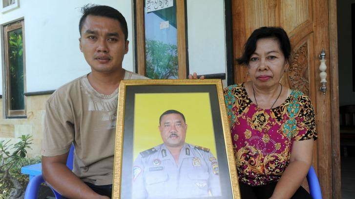 The widow of Wayan Sudarsa, Ketut Arsini, and her son Kadek Toni, hold a portrait of the police officer who was killed on Kuta beach. Photo: Alan Putra
