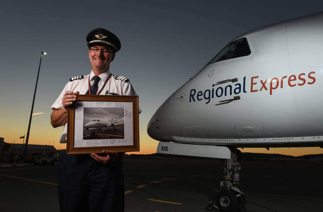 Flying high: Regional Express pilot Barry Anderson with a portrait of a SAAB 340 surrounded by messages of congratulations from fellow Albury airline workers. Picture: MARK JESSER 