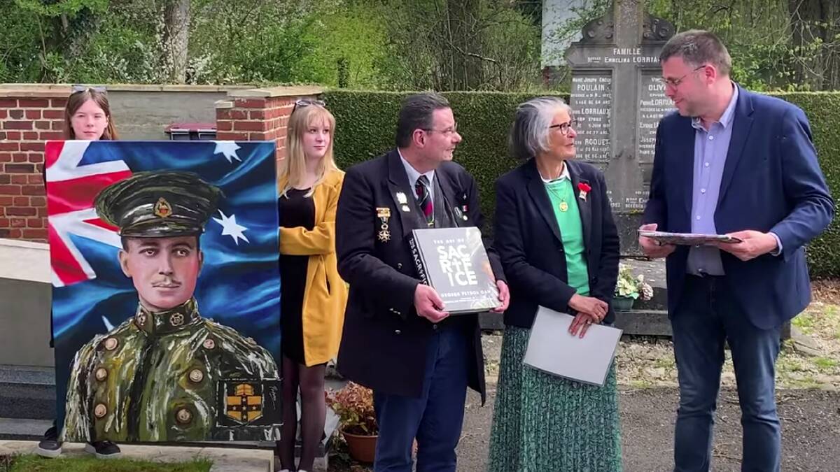 A still from the documentary about Lieutenant Malcolm Chisholm showing the presentation of his portrait of the soldier to the village of Ligny-en-Cambresis in France. Honor Auchinleck is standing between two dignitaries in a green outfit.