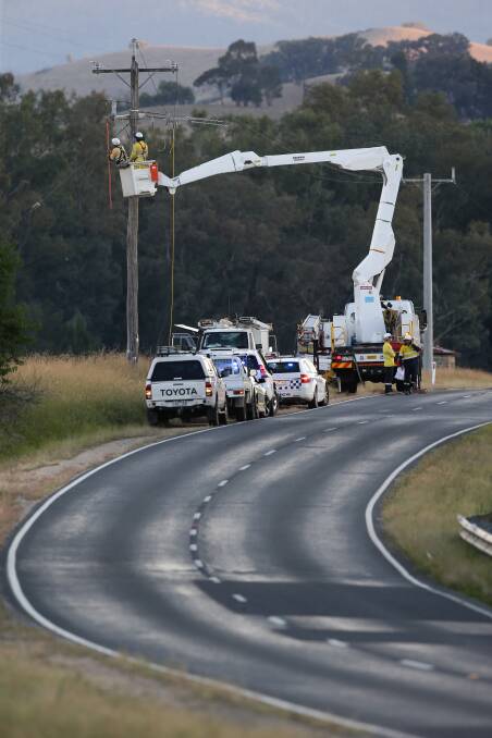 Tough job: Electrical workers examine a pole which carried the line that appeared to be fatally struck by a truck late on Tuesday afternoon. Picture: KYLIE ESLER