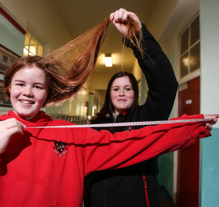 Cutting edge: Year 7 student Talon Peatey stretches out a tape measure to show how much of her hair will be cut in the aid of charity. Her sister Raiyne, 14, is holding her locks. Pictures: JAMES WILTSHIRE