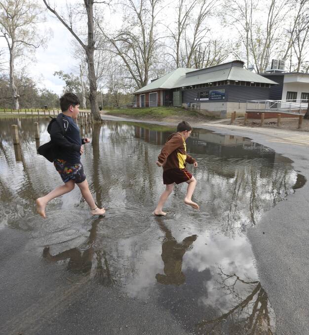 Receding:  Shepparton visitors Tanis Espagne, 9, and Logan Espagne, 7, make a dash for the playground near the River Deck Cafe on Tuesday. Picture: ELENOR TEDENBORG