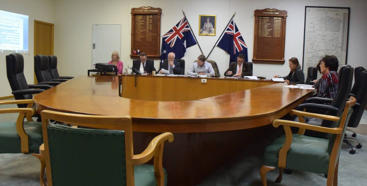 Debut performance: Murrumbidgee Council administrator Austin Evans, below flags, conducts the first ordinary meeting of the new shire in Jerilderie. Chairs usually filled by councillors remained empty for proceedings.