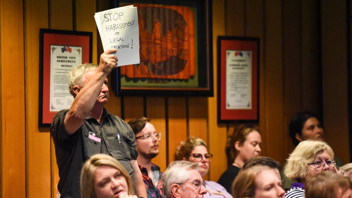 Making a point: Murray Geddes raises his handwritten protest sign to councillors at Monday night's meeting in Albury. Picture: MARK JESSER
