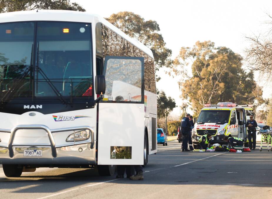Crash scene: Paramedics assist the injured cyclist on Melbourne Road, Wodonga, following the collision on Tuesday morning involving the bus in the foreground. Picture: MARK JESSER