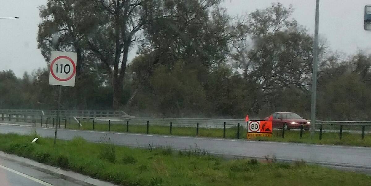 Mixed signals: These signs had motorists confused as they headed north on the Hume Freeway past a group of road workers fixing a guard rail. VicRoads declined to say why the 110km/h signs were not covered.