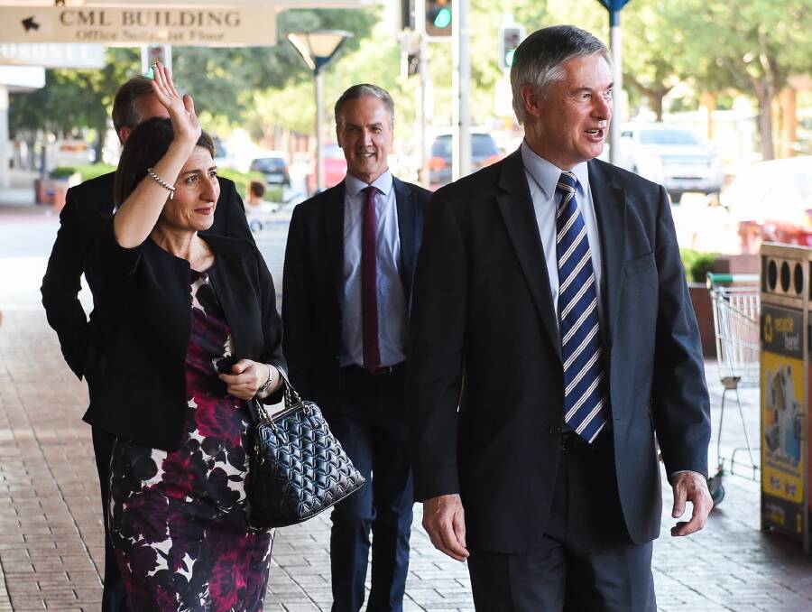 Hello: Gladys Berejiklian waves to protesters upset at the impact of her government's container deposit scheme. She was walking with Albury mayor Kevin Mack (obscured), former Federation Council administrator Mike Eden and member for Albury Greg Aplin. Picture: MARK JESSER