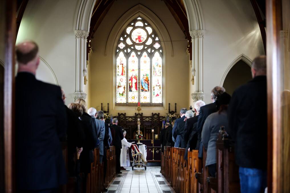 Ashes to ashes: Reverend Christine Moimoi blesses Arch McLeish's coffin which was draped in a naval ensign and topped with his sailor's cap from HMAS Quickmatch. Picture: JAMES WILTSHIRE 