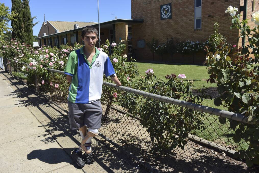 Making waves: Swimmer Thomas Burton outside his high school. He does not always wear prosthetic arms, being able to write by putting his stumps together. 