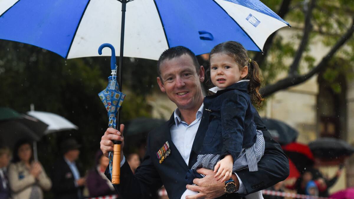 Family moment: Thurgoona's Michael Pitman had his daughter Matilda, 2, in one arm and an umbrella in the other as he marched along Dean Street.  