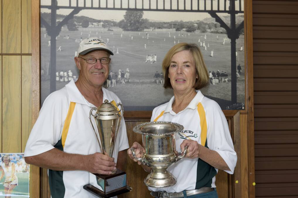 READY TO GO: Ken and Dianne Wurtz show off the tournament cups in front of a picture of the 1933 Albury Easter Open. Picture: SIMON BAYLISS