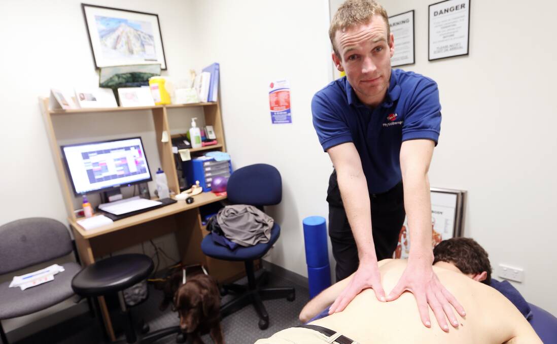 HANDS ON: Daniel Searle, with trusty guide dog Bear in the background, has started a job as a clinical 
physiotherapist. Daniel lost 95 per cent of his vision as a teenager. Picture: JOHN RUSSELL