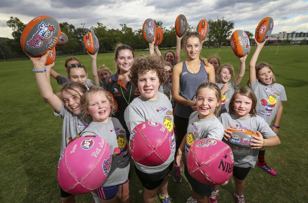 GIRLS' TURN: Charlee Pearce, 8, Kylie Breed, 9, and Charlotte Packer, 7, holding up pink footballs at their Auskick clinic. Picture: JAMES WILTSHIRE