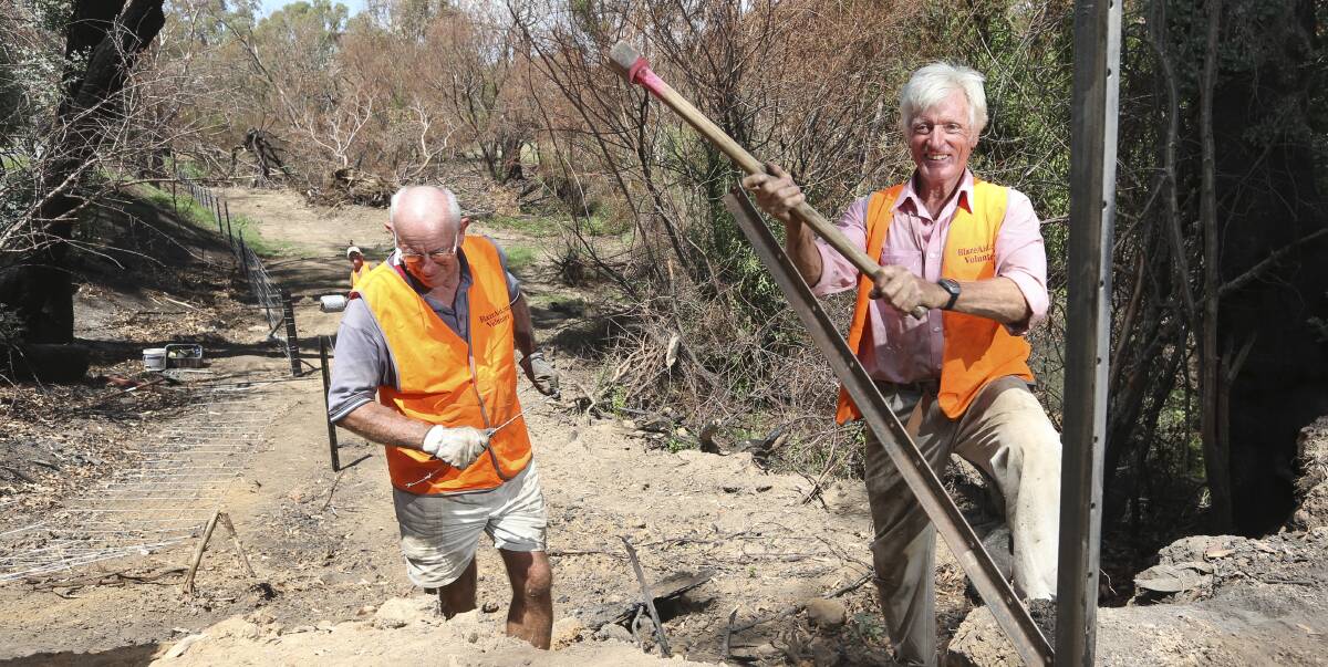 HAMMER TIME: Stuart Russell of Wangaratta and Doug Taylor from Coonabarabran work on the final 15-metre stretch of an Indigo Creek property's fence. Picture: ELENOR TEDENBORG