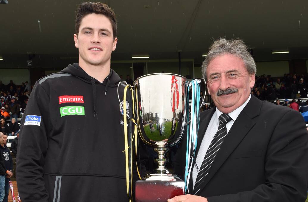 PROUD PIE: Collingwood star Jack Crisp, left, and SS&A Club chairman Eddie Dunlop hold the premiership cup before the O and M grand final.
