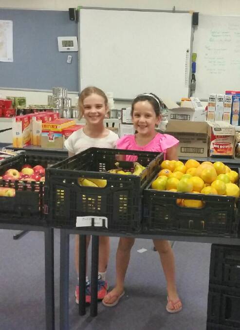 YOUNG HELPERS: Emily McLean, 7, and Alexis Proctor, 7, both going into Year 2 at the school, help with the fruit.