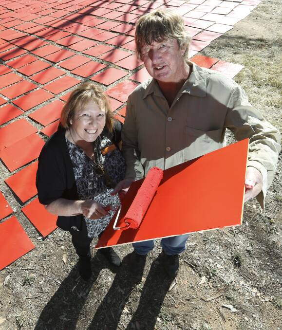 VOLUNTEERS: Jemma Toohey and garden manager Ricky Taylor painting red tiles for a Guinness World Record attempt at Albury Sports Ground. Picture: ELENOR TEDENBORG
