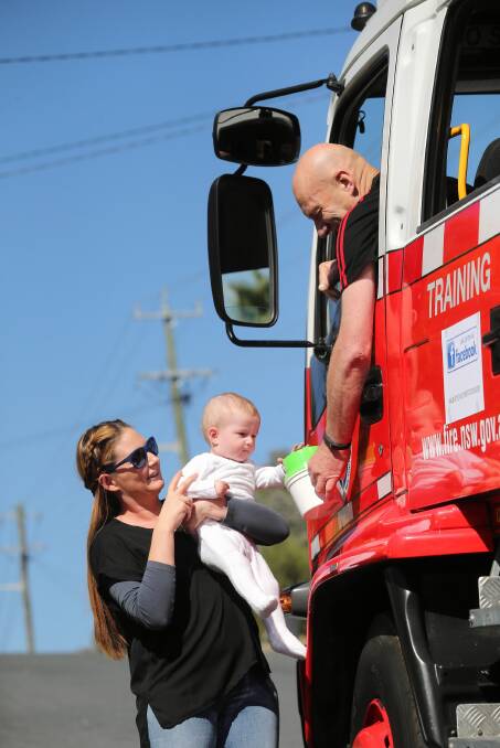 Kirsty Rowe lifts her son Henry, 8 months, so he can donate to John Vandeven. Picture: JOHN RUSSELL