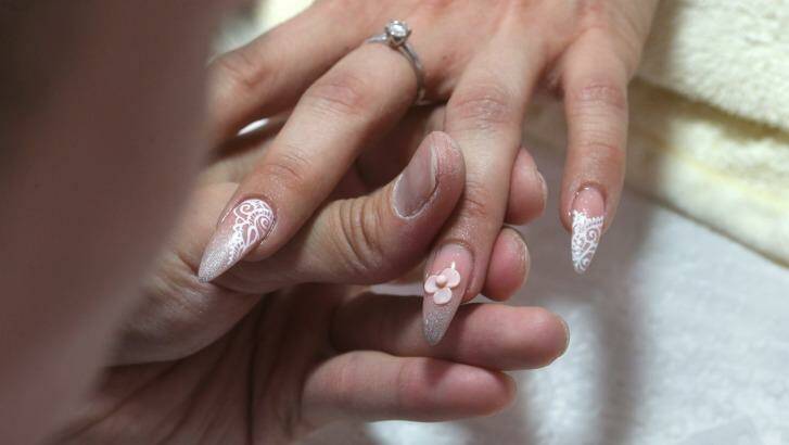 Jonny Diep Pham makes acrylic flowers bloom on his client's fingernails. Photo: Tony Walters