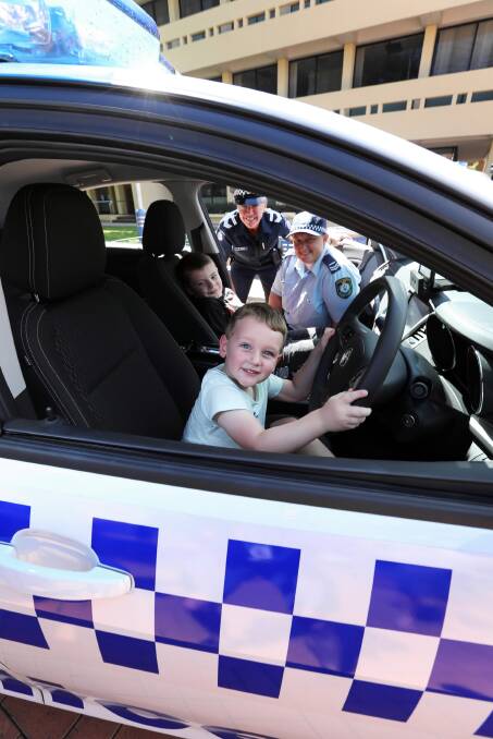Charlie McCormack, in driver’s seat, 4, of North Albury, and Reilly Grant, 5, of Albury, are shown a police car by Leading Senior Constable Raquel Vogel, of Wodonga police, and Senior Constable Alicia Langman, of Albury police, in QEII Square. Picture: MATTHEW SMITHWICK
