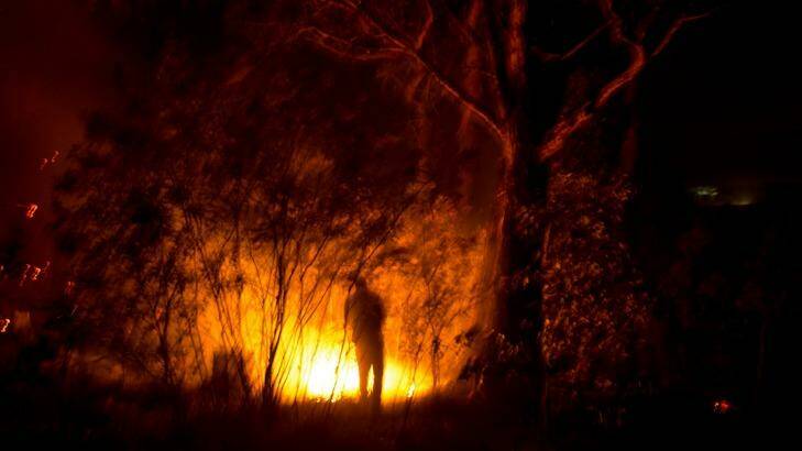 Long, hot summer: Adam Watkin douses spot fires near his home on Three Chain Road near Lancefield in Victoria. Photo: Justin McManus
