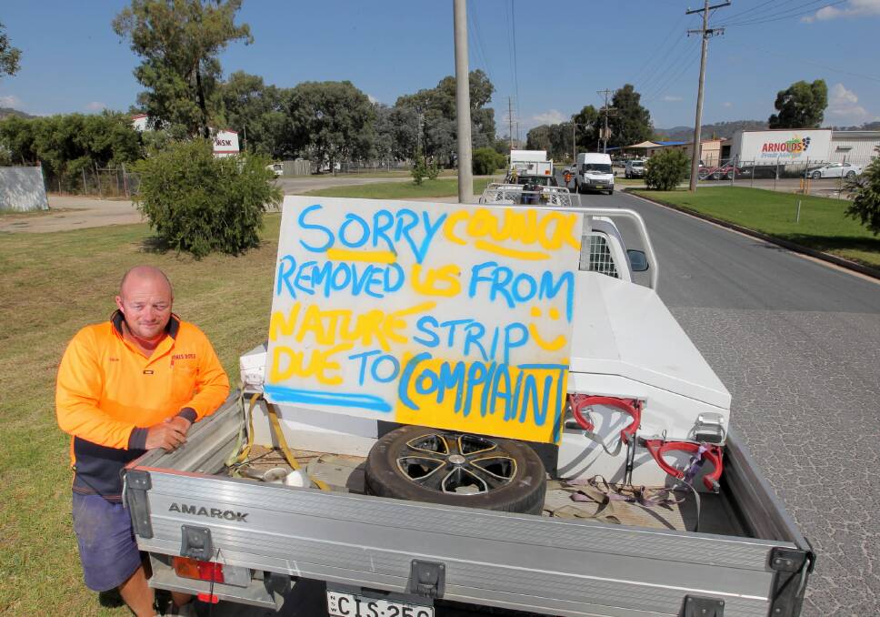 Rick Doyle, left, put this sign in the back of ute parked legally in the street to protest Wodonga Council telling him he can no longer park on the gravel area of the median strip in front of his business. Picture: DAVID THORPE