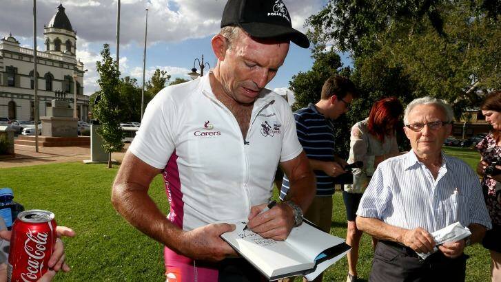 Mr Abbott signs a copy of his book. Photo: Alex Ellinghausen