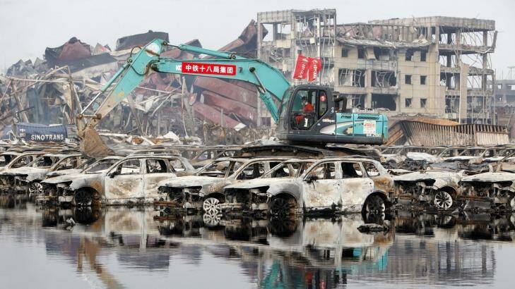 Rescuers and machines clean up burnt vehicles at the blast site. Photo: ChinaFotoPress/Getty Images
