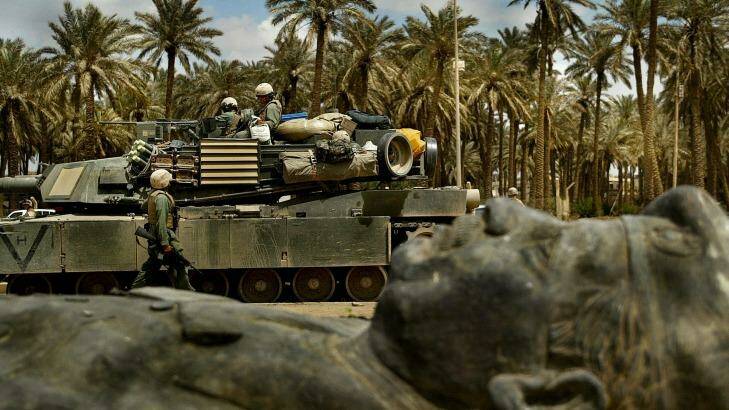 A US tank unit passes one of the many fallen statues of former Iraq dictator Saddam Hussein, in Baghdad in 2003. Photo: Kate Geraghty 
