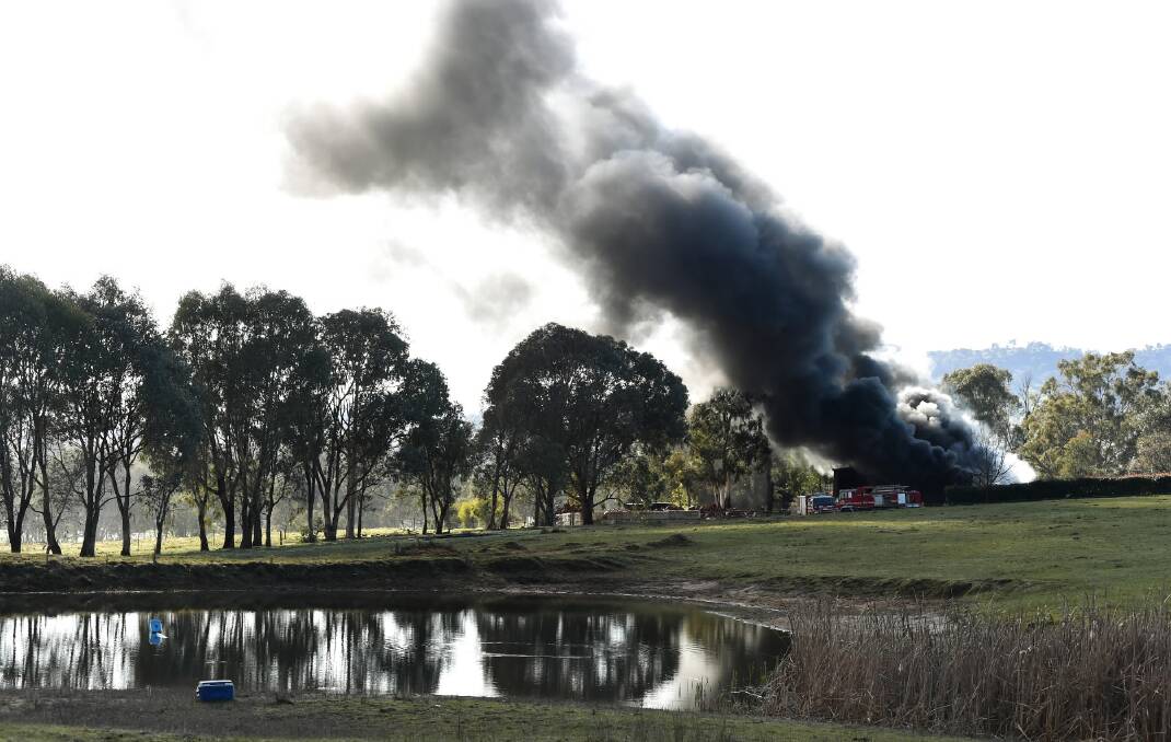Black smoke pours from a shed during a fire at Kiewa yesterday. Pictures: MARK JESSER