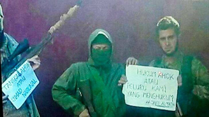 Members of the Syria-based jihadist group Jabhat Fatah al-Sham hold a sign that reads "Punish Ahok or our bullets will". Photo: Supplied