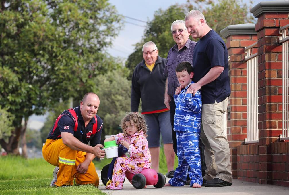 Wodonga firefighter Rowan Montoneri accepts some early morning coins from Tully Whitehead, 3, as Geoff Burton, Geoff McKernan, Max Whitehead, 7, and Paul Whitehead look on. Picture: JOHN RUSSELL 
