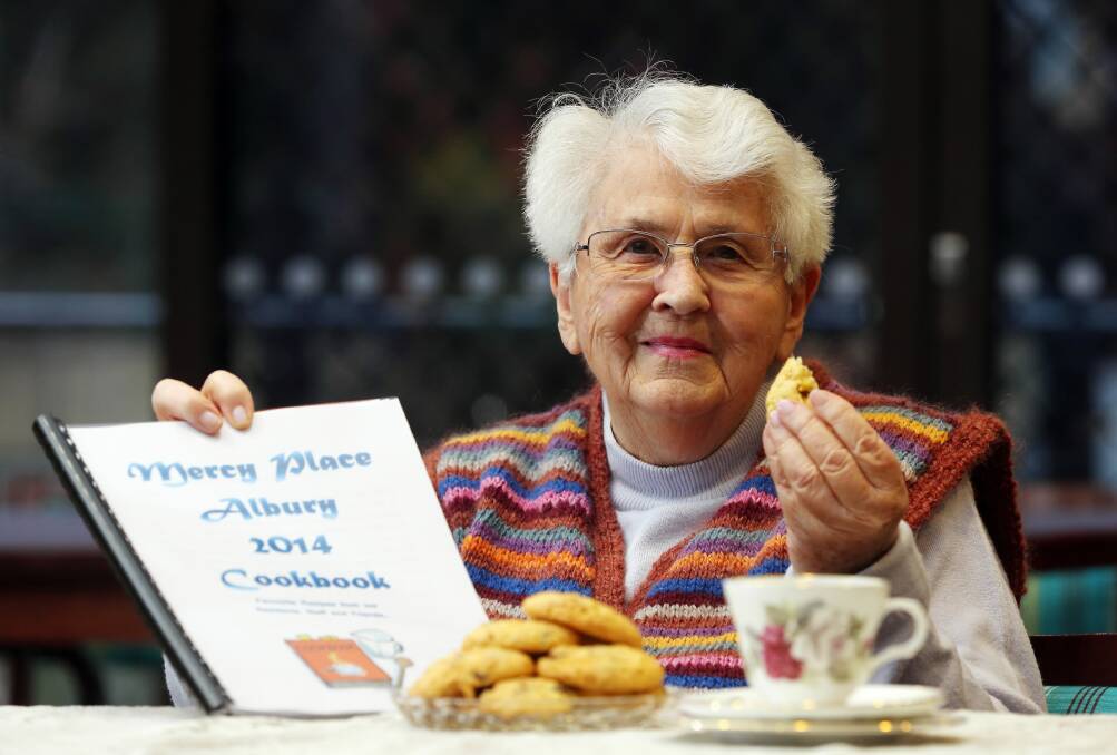 Mercy Place resident Audrey Stenson samples some cookies from the Mercy Place Albury 2014 Cookbook. Picture: JOHN RUSSELL