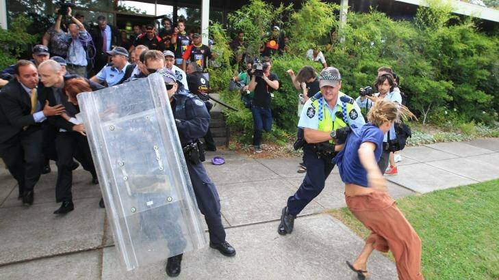 Julia Gillard and Tony Abbott shielded from protesters. Photo: Alex Ellinghausen
