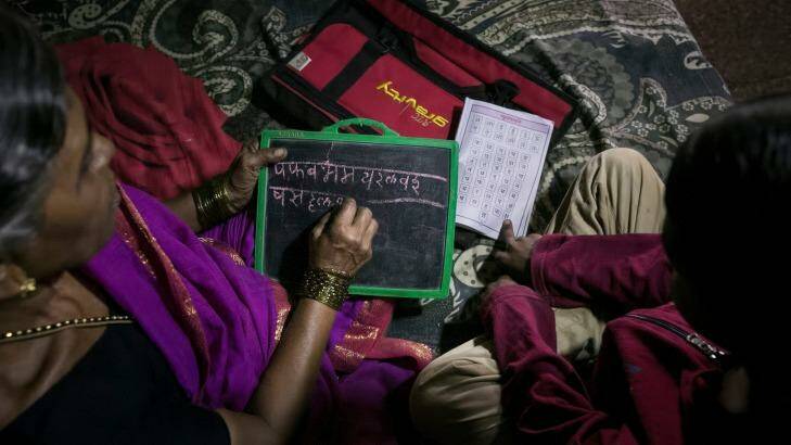 7-year-old Sujal helps his grandmother, Kanta More, 65, with her schoolwork.  Photo: Allison Joyce/Newslions