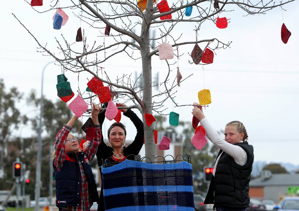 Patrick, 10, Kate, and Millie Barrette Cummins, 13, yarn bomb trees in Mate Street Lavington to encourage people to smile on miserable winter days. Picture: MATTHEW SMITHWICK
