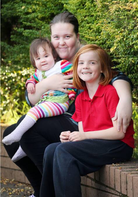 Chelsea Sparkes, of Springdale Heights, with her daughters Ella, 19 months, and Kirsten, 8, who were born with a rare illness. Picture: JOHN RUSSELL