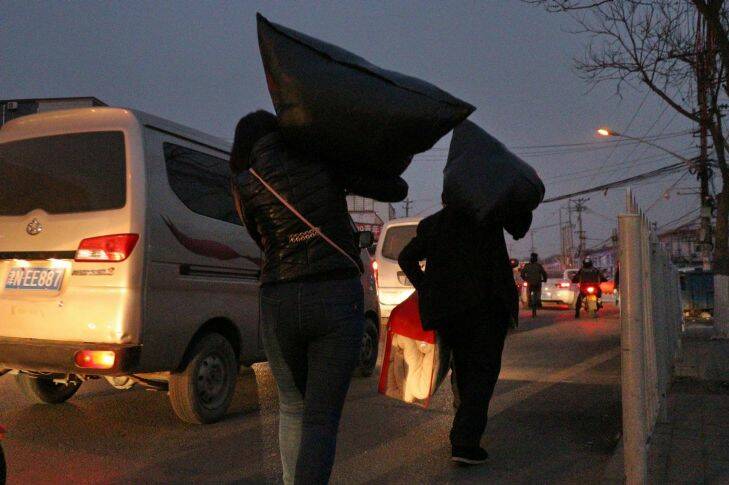 Yan Erjun, 50, a migrant construction worker from Sichuan Province and his wife Zhou Xiaomei, 44, a house cleaner moving their home by carrying bags on his shoulders at Picun Village in Chaoyang District of Beijing on November 27, 2017. Yan and his wife were given a very short notice to move out from their rented apartment in which power supply was cut off. A notice on the midday of November 27 asks all apartments for rent in the village should be cleared off by 6:00PM of the same day. Later the day, the deadline was postponed to December 1, 2017. Picun Village, in the eastern outskirt of Beijing is home some 20,000 migrant workers as it affords relatively cheap accommodation(from 500-1,000rmb/m). Beijing municipality government has launched a 40-day check and rectification of hidden dangers after a fire in Daxing District of Beijing on November 18 claimed 19lives. The municipalty has been criticized of driving out "low-end" population which Beijing Administration of Work Safety denied on Sunday(November 26). .